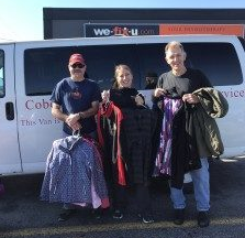 coats for kids drive three people holding clothing infront of a van