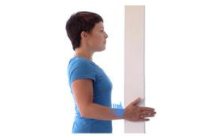 a woman holds wall and faces it sideways
