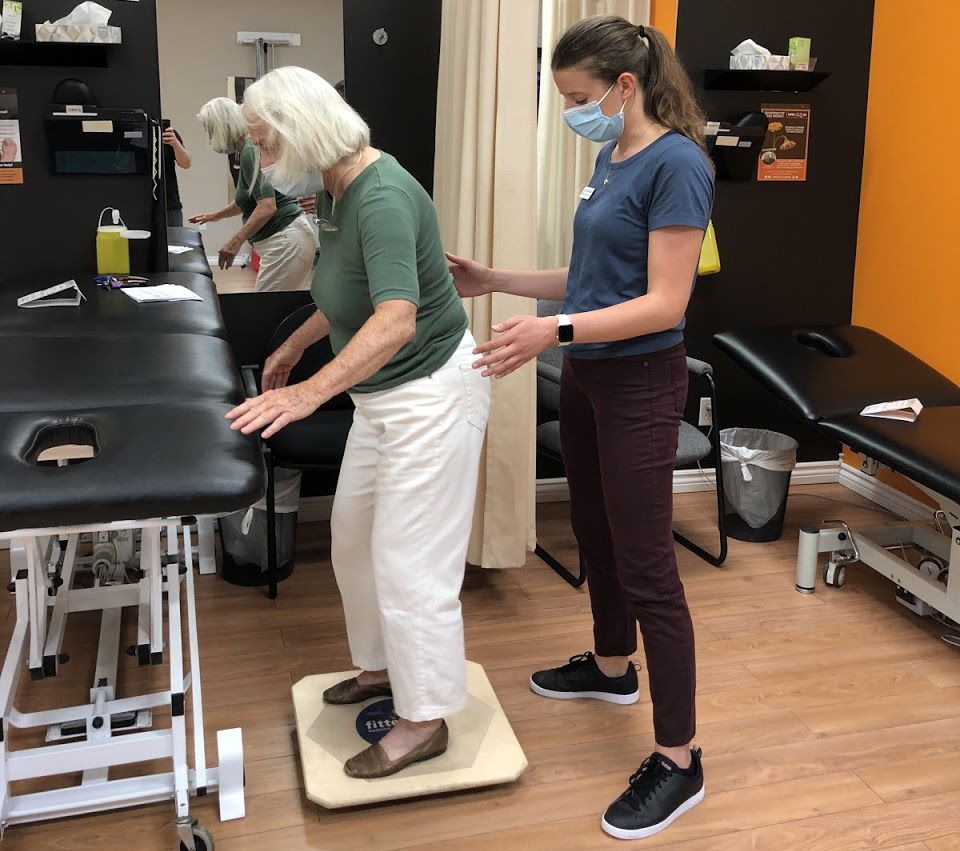 Wefixu Port Hope physiotherapy clinic physio assistant helping patient train her balance on a balance board