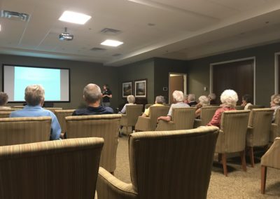 a group of elderly seated listening to staff giving presentation at front